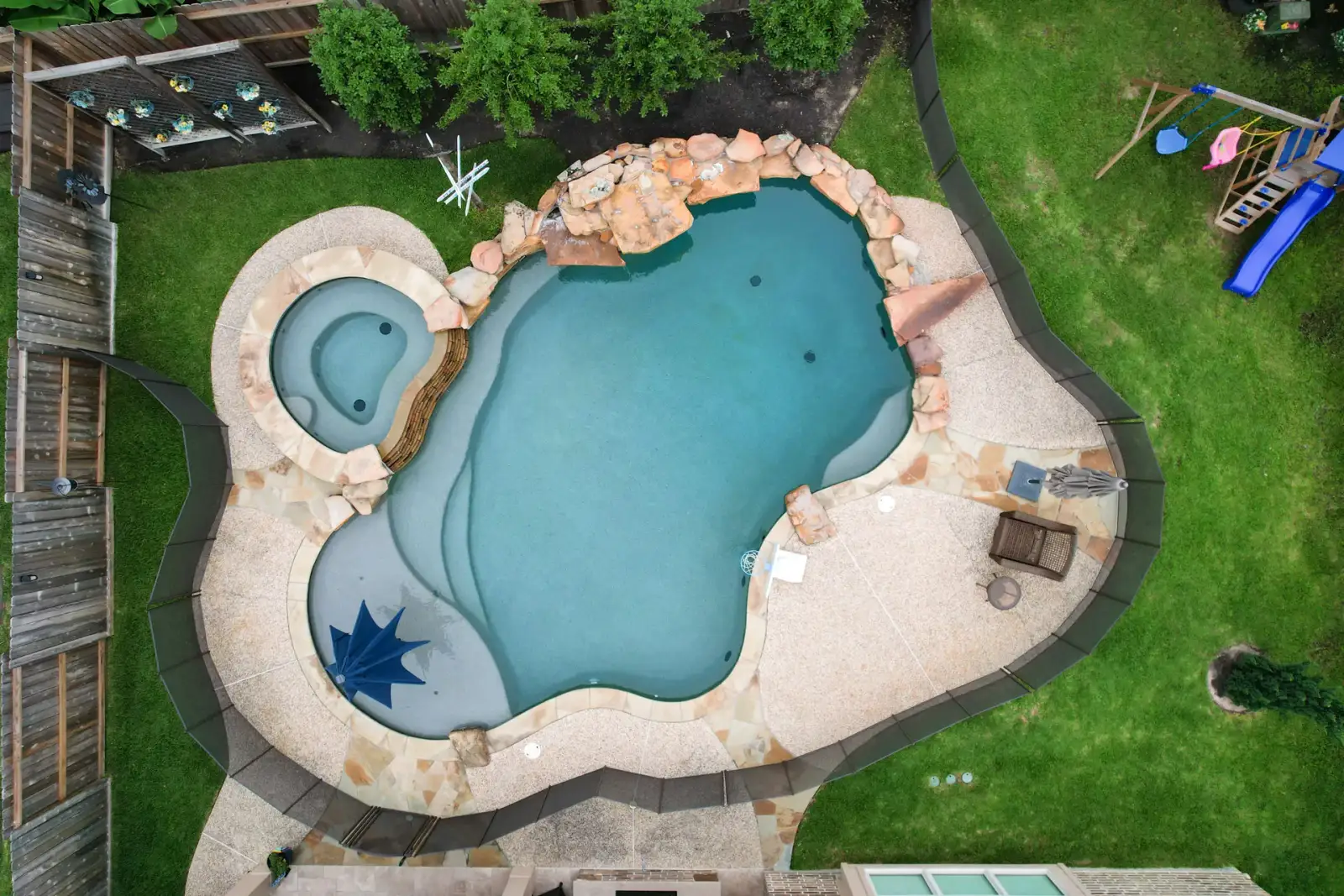 Aerial view of a freeform pool and spa with a rock waterfall