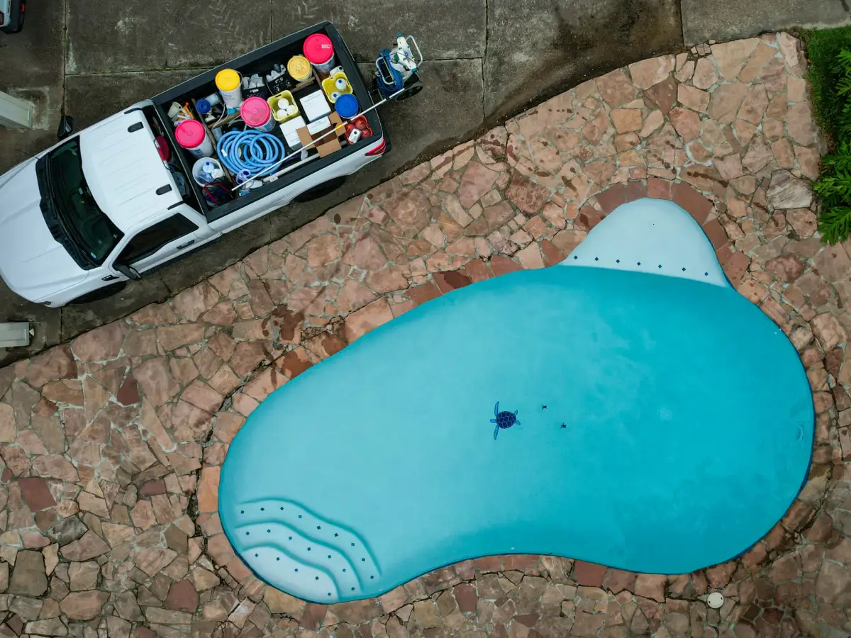 Overhead drone view of an Aloha service truck parked beside a freeform pool with a flagstone deck
