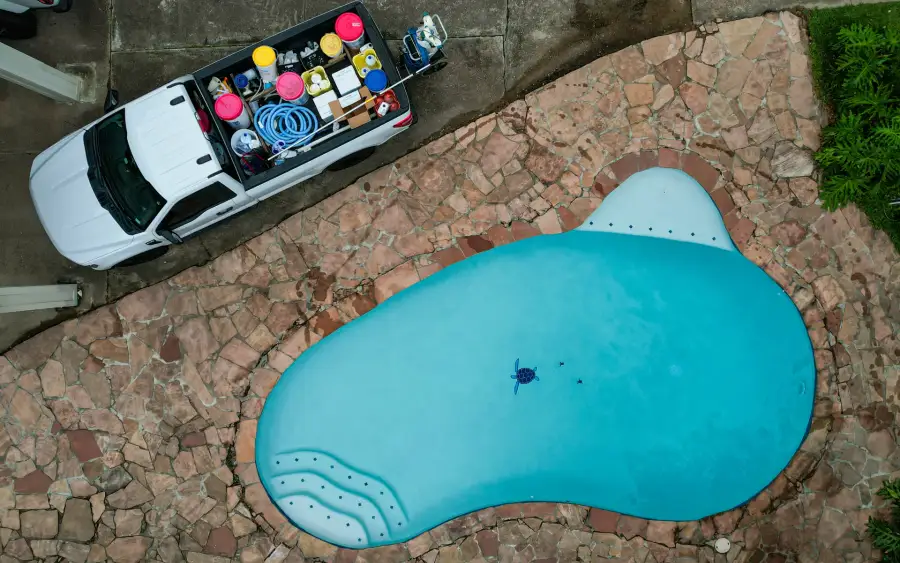 Overhead drone view of an Aloha service truck parked beside a freeform pool with a flagstone deck