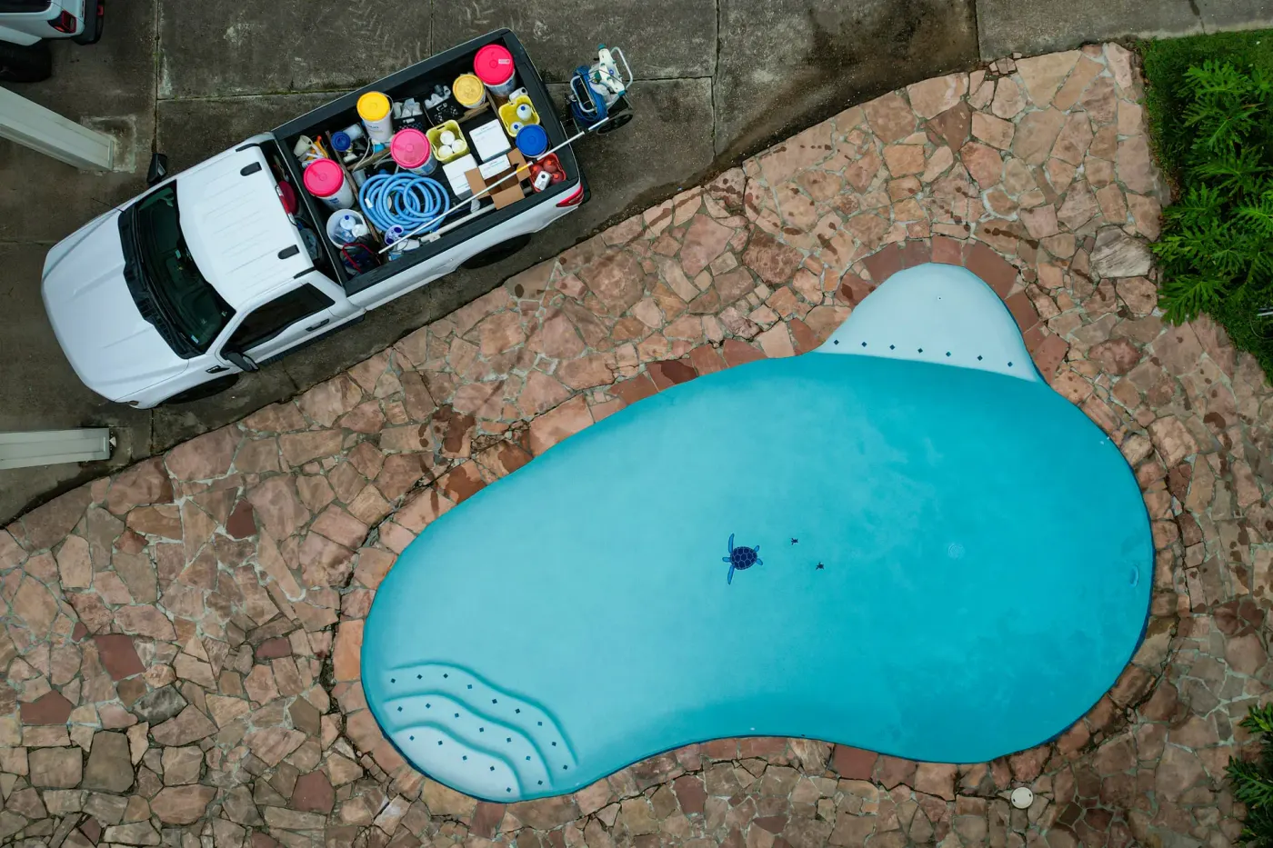 Drone view of an Aloha service truck parked on the driveway beside the same flagstone pool