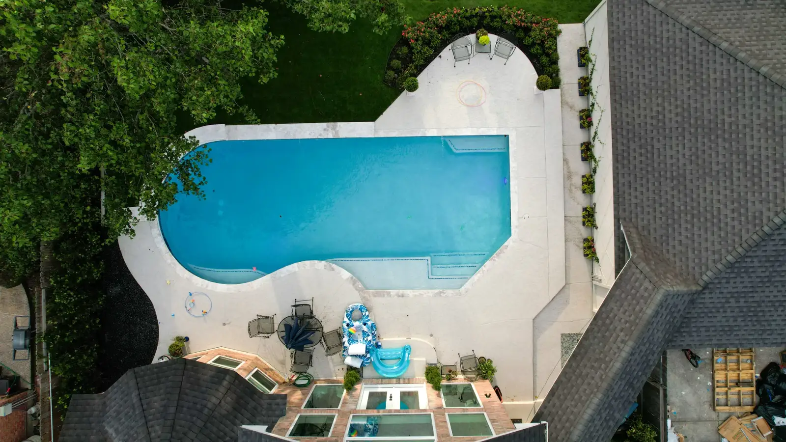 Overhead view of a rectangular pool with a white deck beside the house