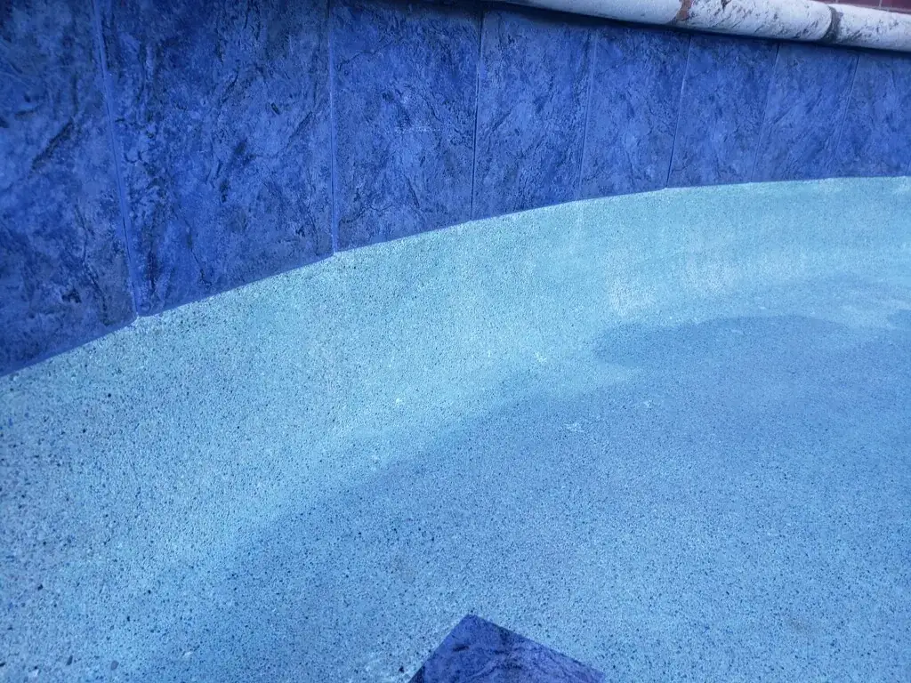 Waterline tile and speckled pebble pool finish seen close up under clear water