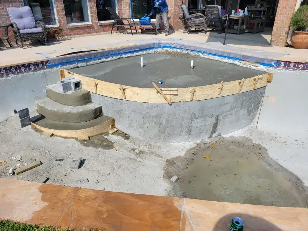 Pool mid-remodel with timber forms shaping new curved entry steps and fresh shotcrete