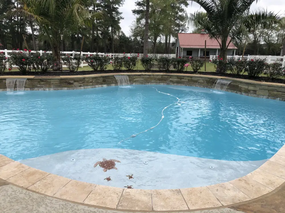 Pool with three sheer-descent waterfalls from a stone wall and turtle mosaics on the shallow entry