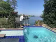 Aloha technician cleaning a waterfront pool with blue waterline tile using a telescopic pole