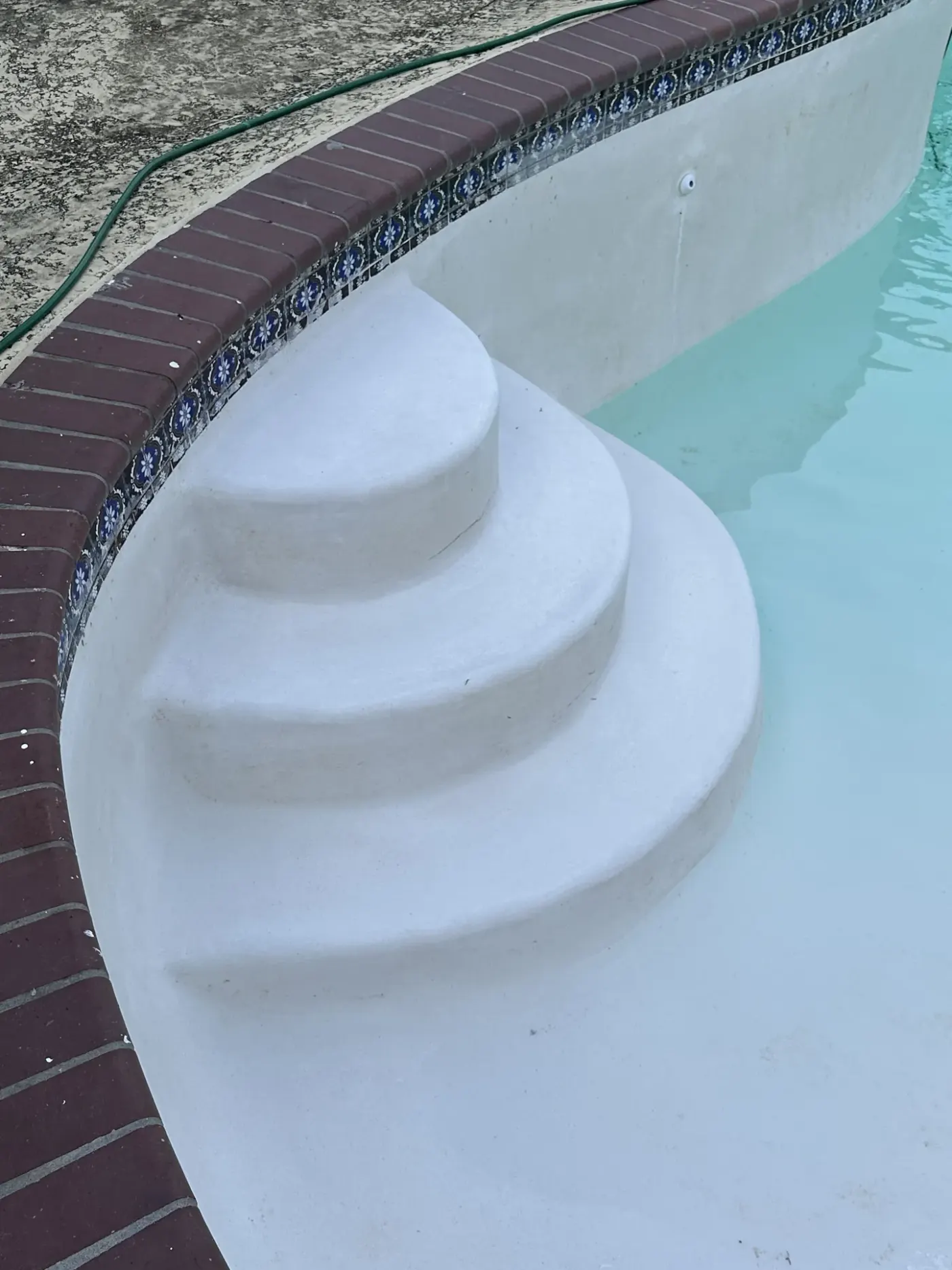 The same curved entry steps after replastering in smooth white plaster below brick coping